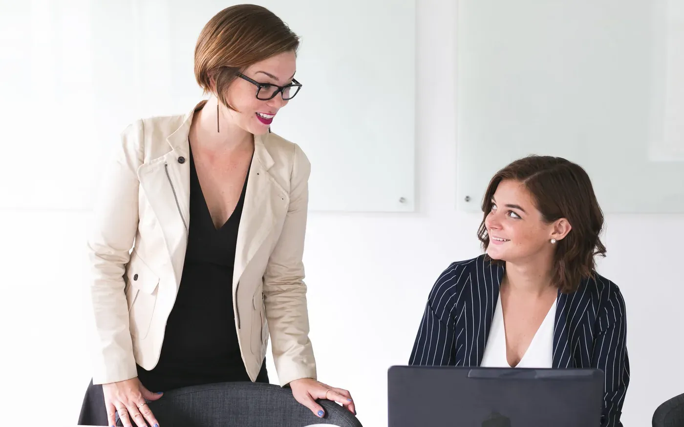 Two people discussing figures behind a laptop.