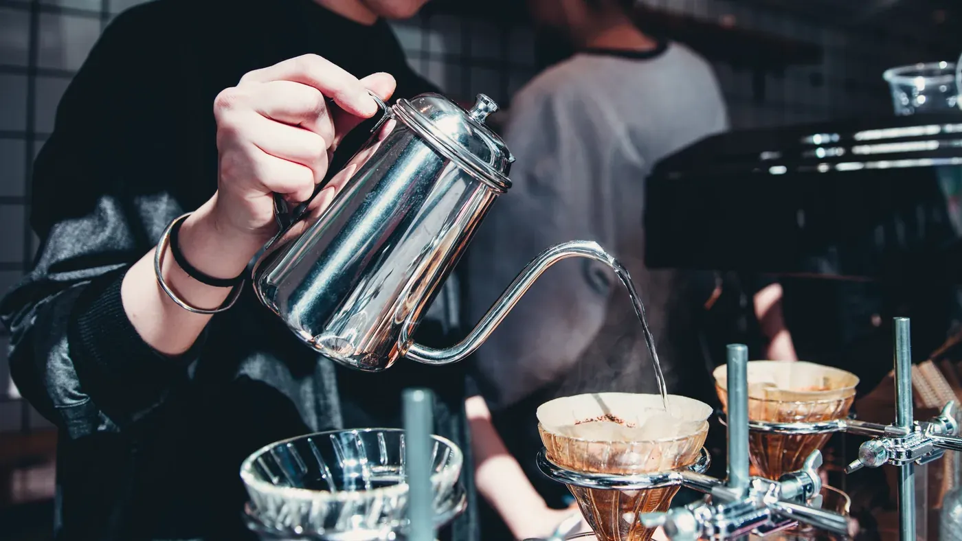 A barista pours filter coffee in a café.