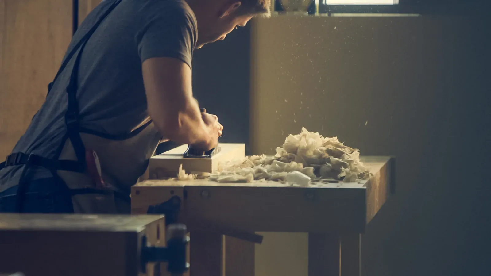A craftsperson works with concentration at a bench.