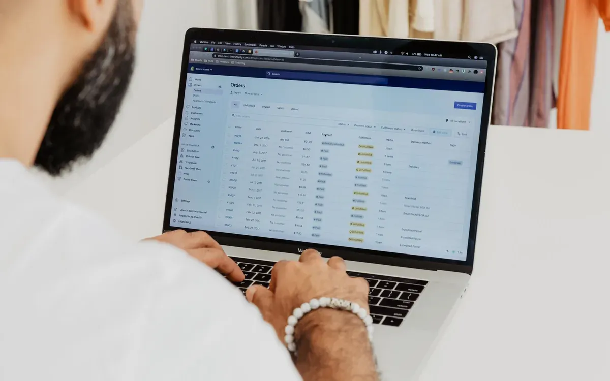 A business owner works on a laptop with an overview on screen.