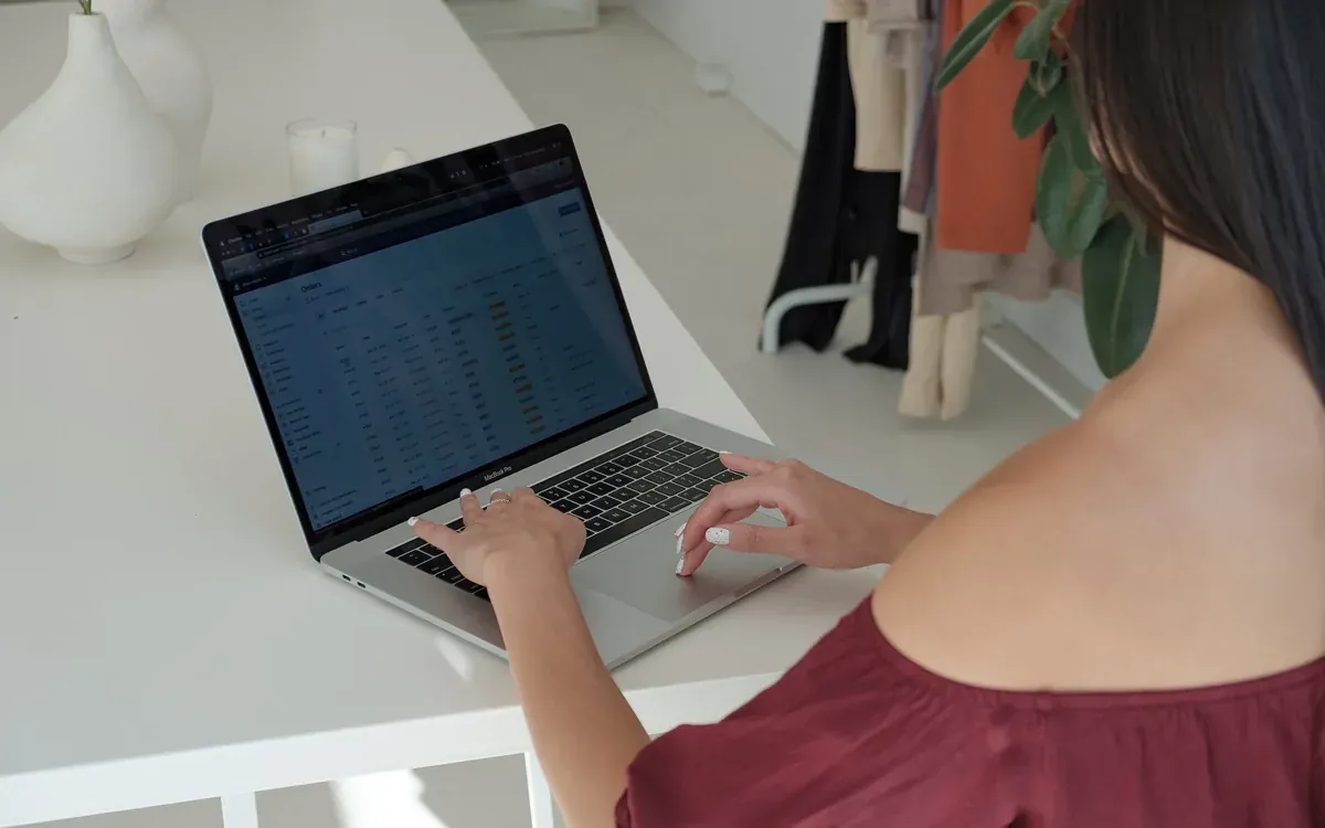 A business owner reviews figures on a laptop at a bright desk.