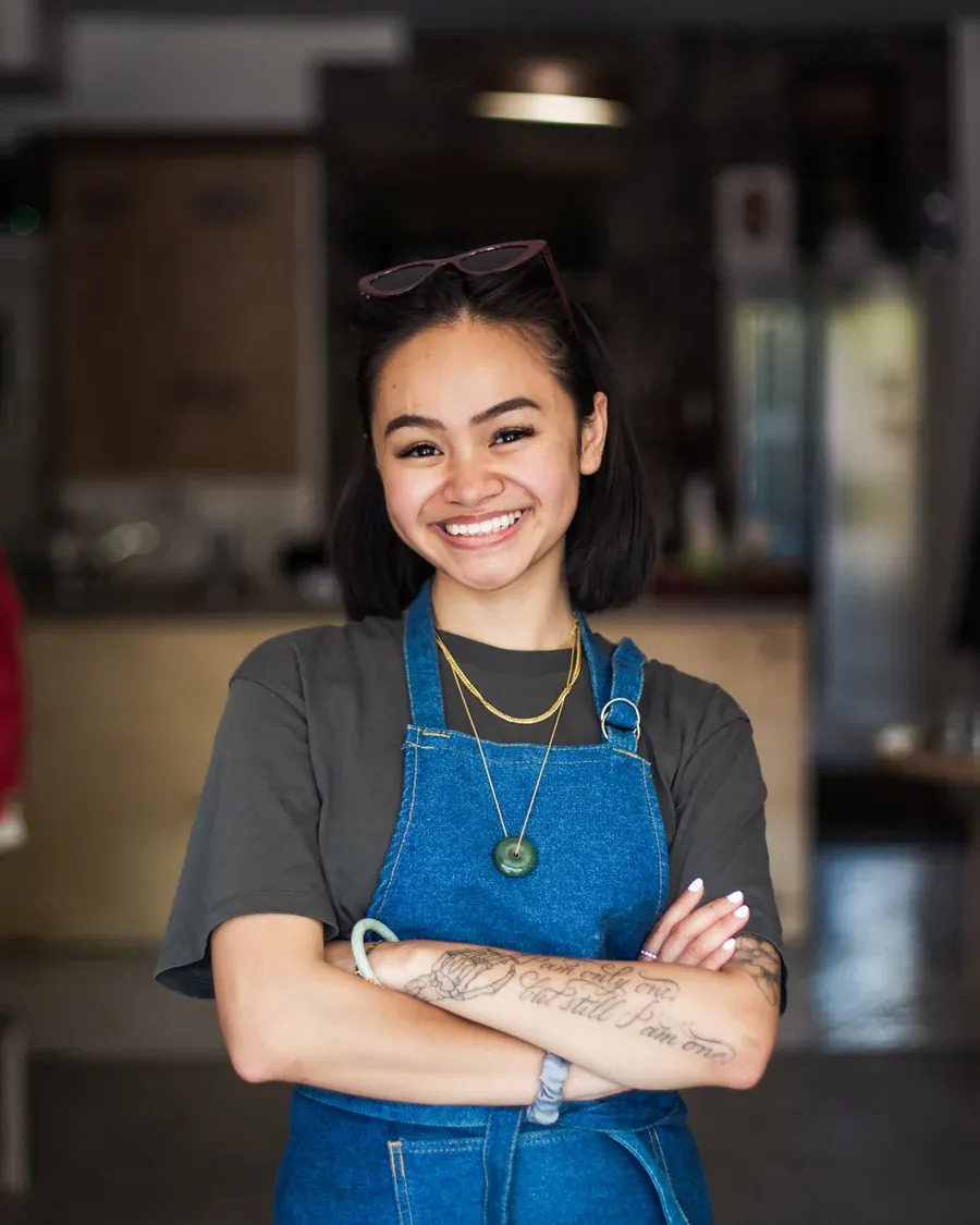 A shop owner stands with folded arms in her own store.